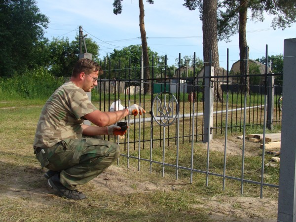 Владислав Куценко фарбує передню секцію паркану
