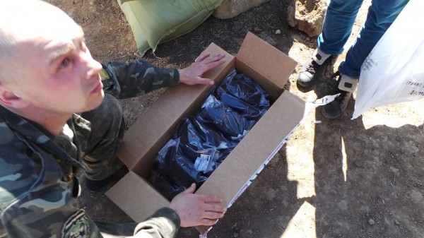 Український вояк оглядає пакунок з тактичними окулярами ESS